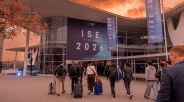 Attendees arriving at Integrated Systems Europe (ISE) 2026 at Fira de Barcelona Gran Via, walking toward the venue entrance beneath large ISE 2026 banners at sunset.
